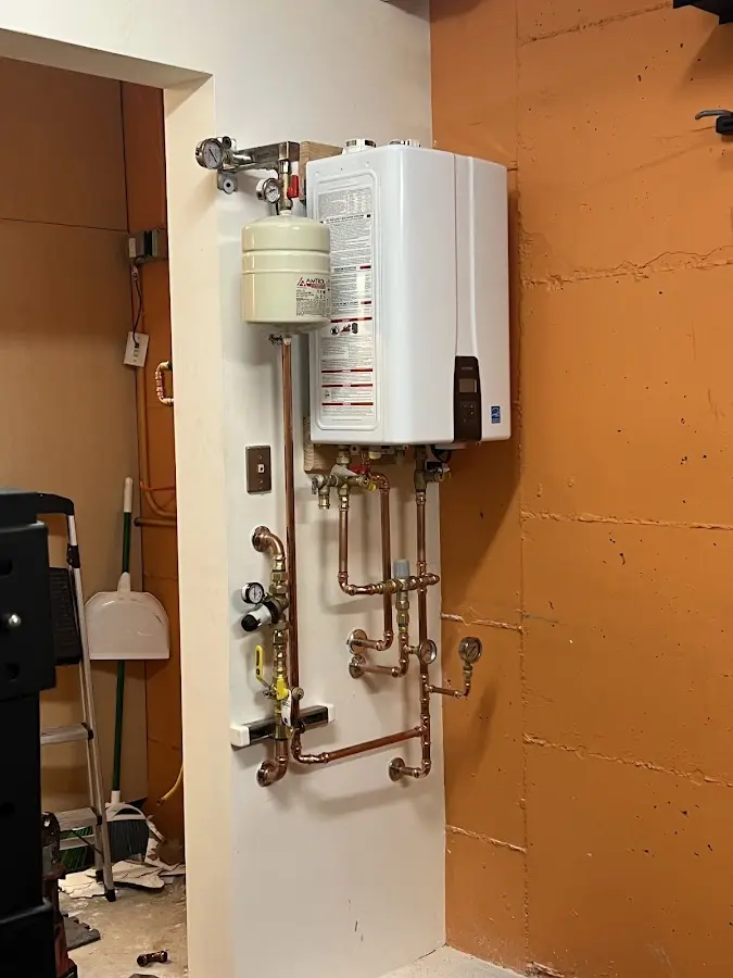Plumbing technician inspecting water heater connections in Ashwaubenon